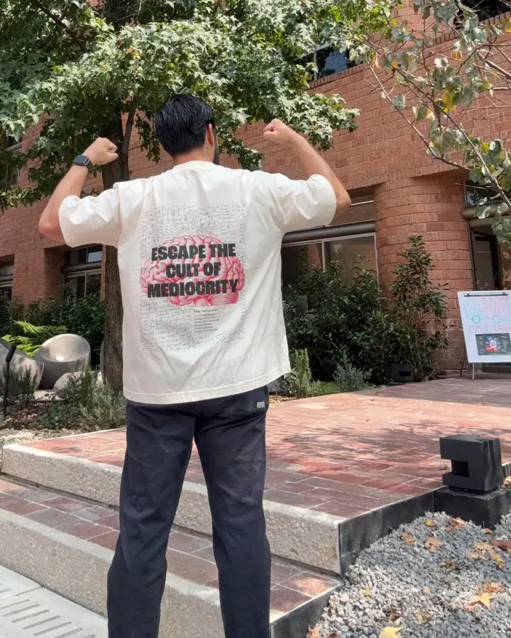 Aquiles de espaldas con la WILD SPARK y los brazos arriba, frente a un edificio de ladrillo
